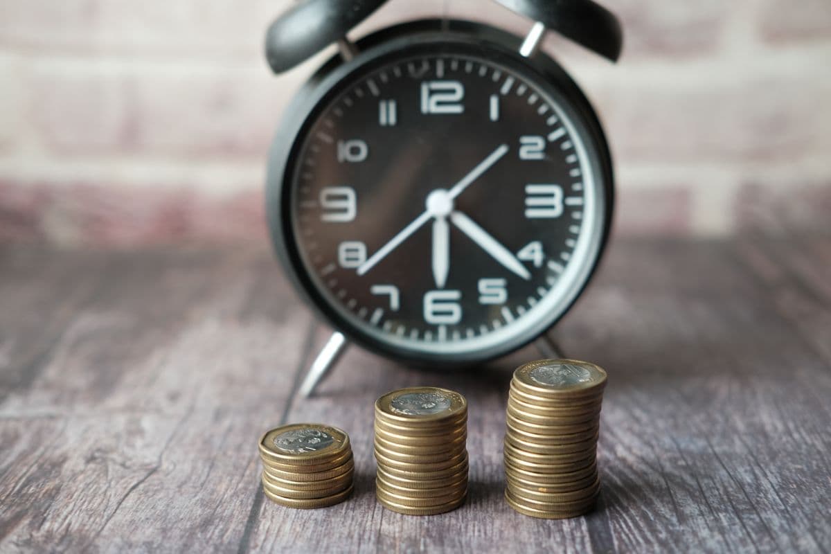A clock beside stacked coins